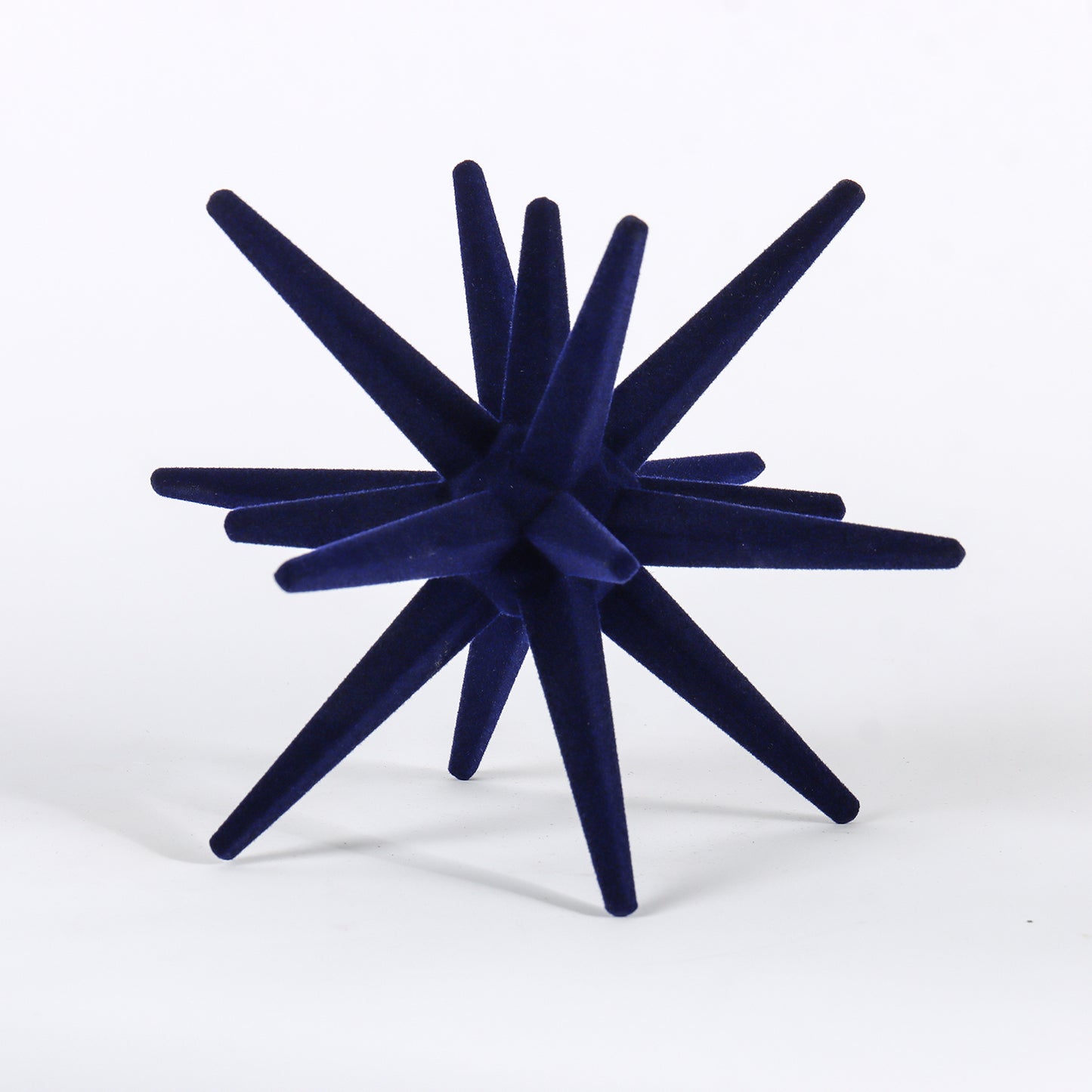 Navy blue decorative object with starburst design on a white background