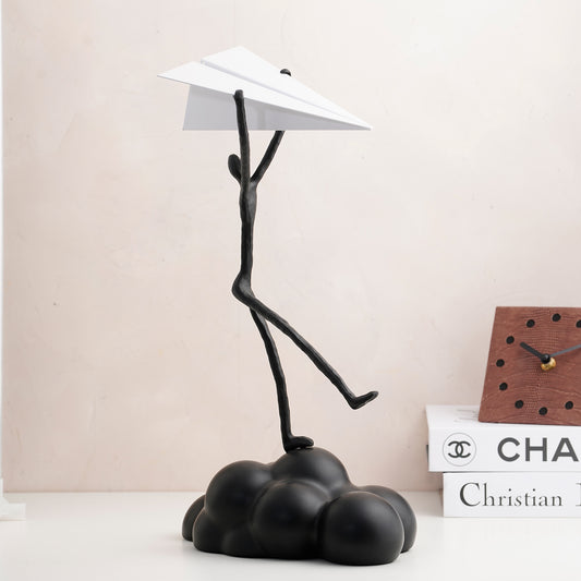 Decorative Modern black human sculpture standing on a cloud with a paper plane in hand