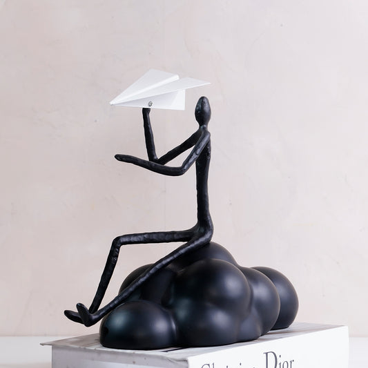Decorative Black Human Figurine sitting on a cloud with a Paper Plane in Hand