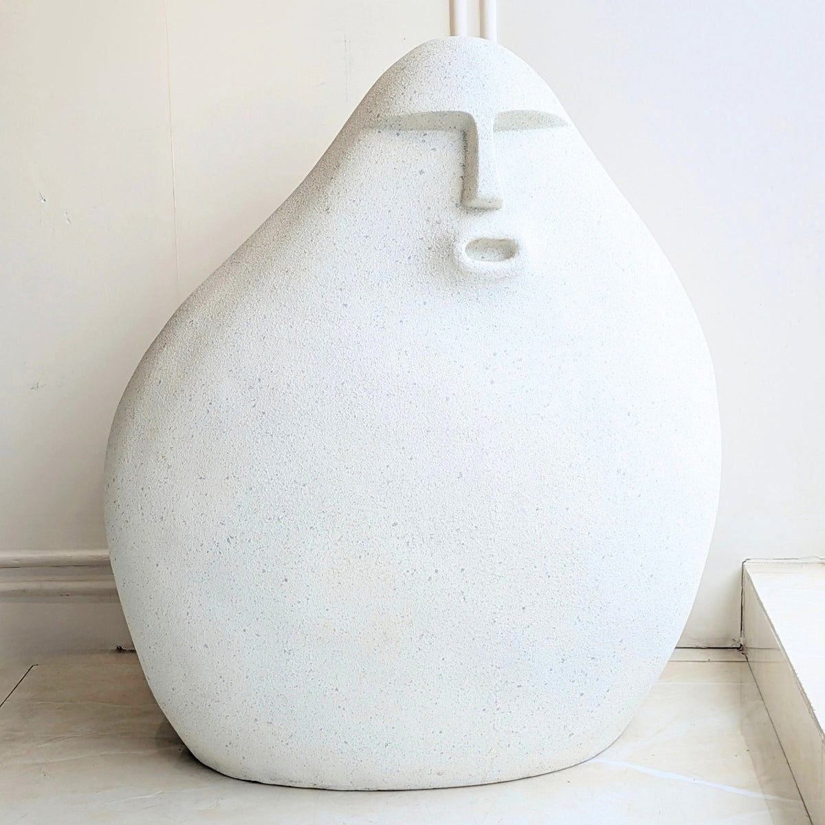 Carven small textured resin floor sculpture with a carved stone finish and abstract human face
