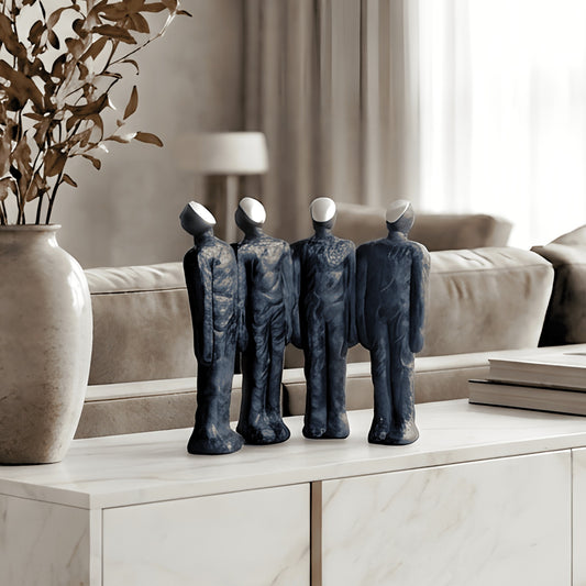 Ensemble four abstract resin human figures styled on a marble console in a luxury living room