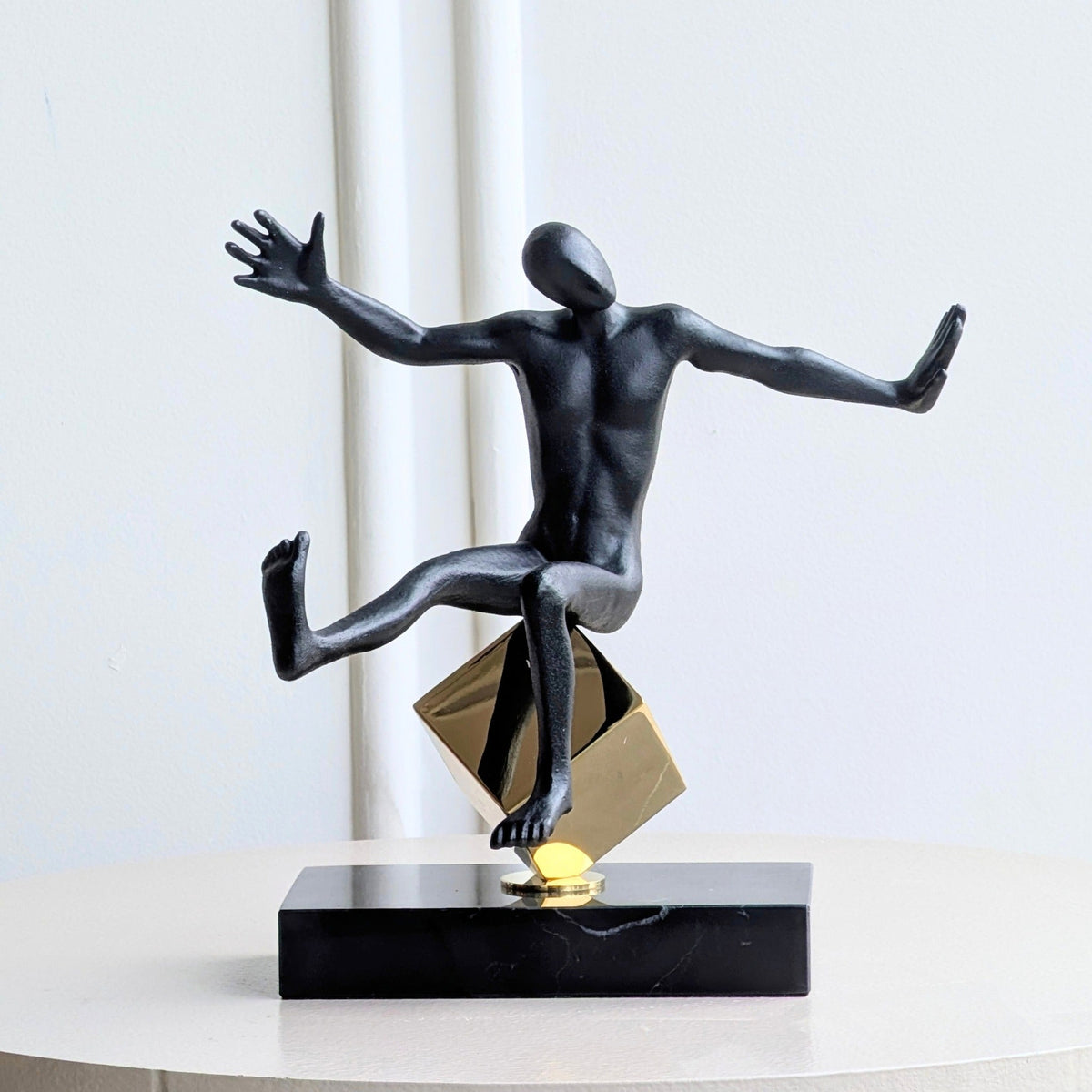 Front view of the Kinesis reaching human showpiece in black and gold metal