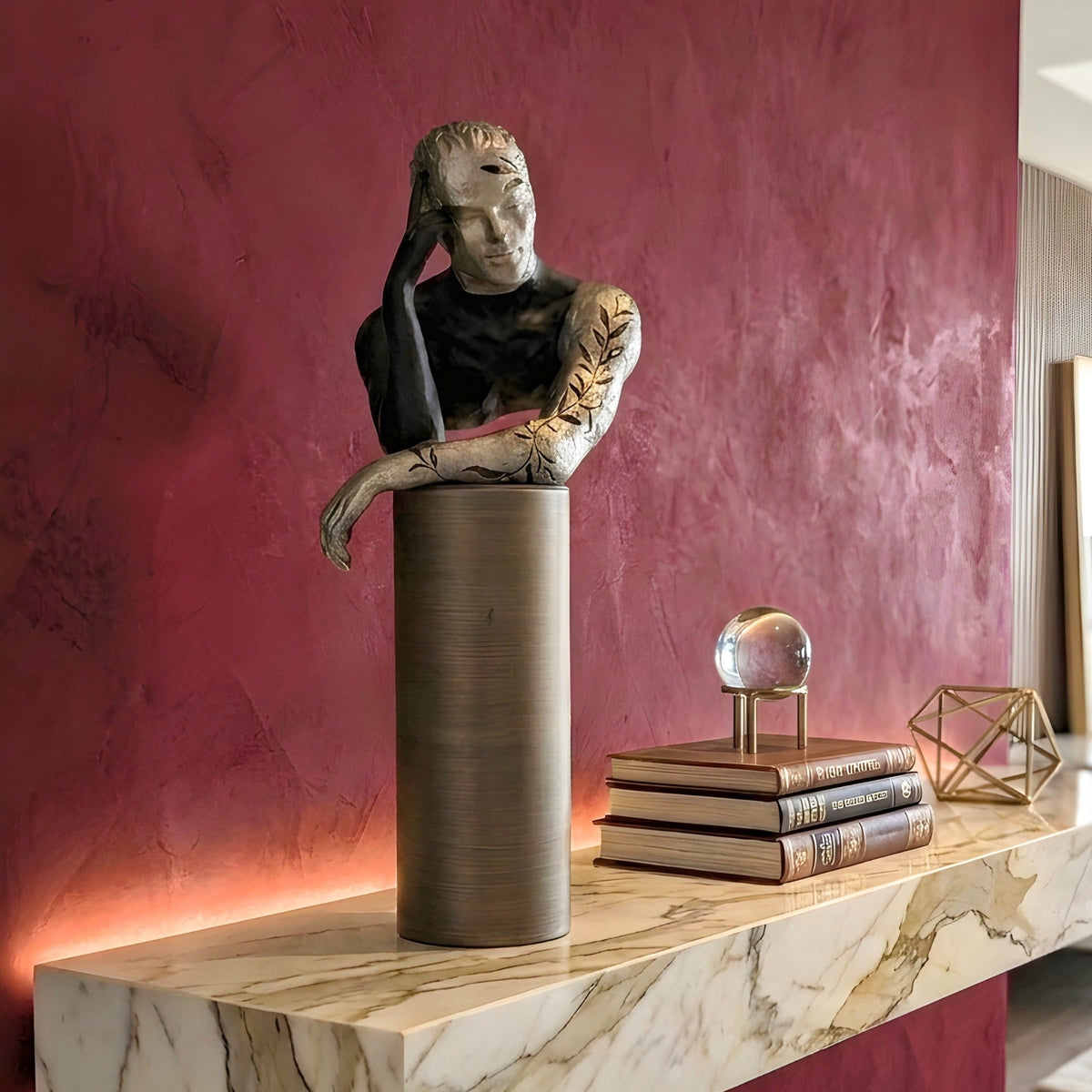 Pensive metal and resin human figurine styled against a rich red feature wall