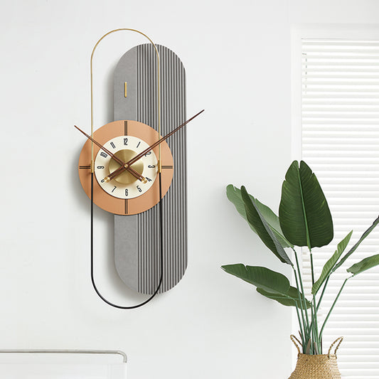Modern vertical wall clock with a decorative design on a white wall with a plant in the corner.