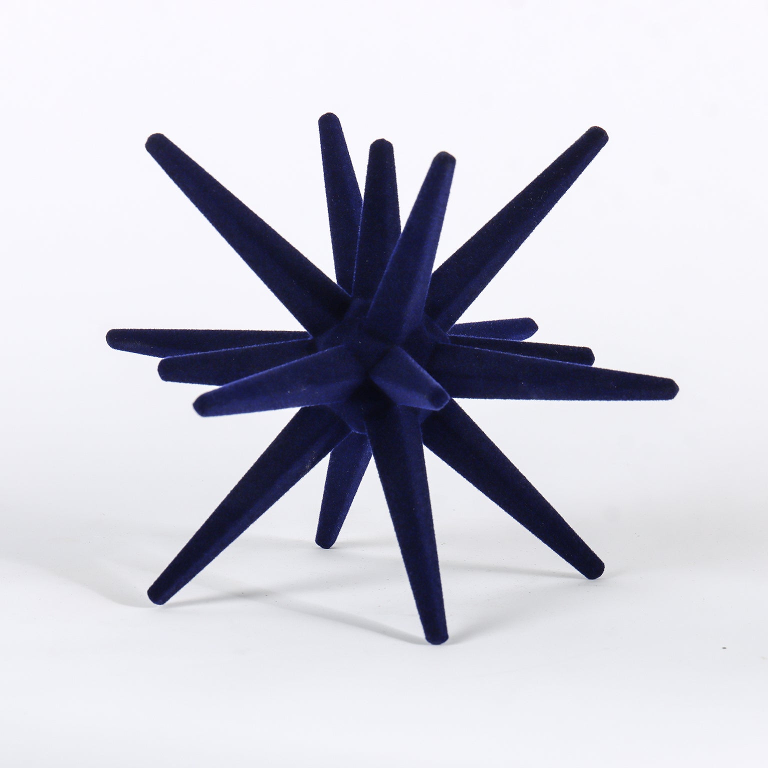 Navy blue decorative object with starburst design on a white background