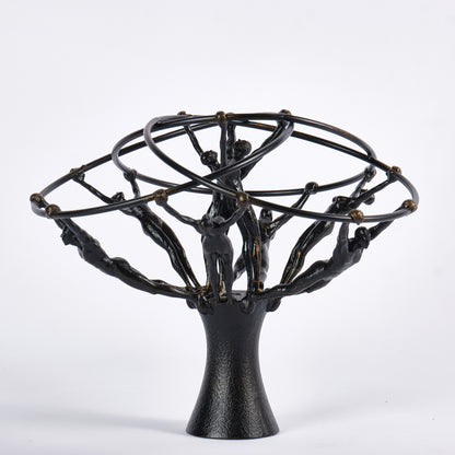 Black metal sculpture with abstract human figures on a white background