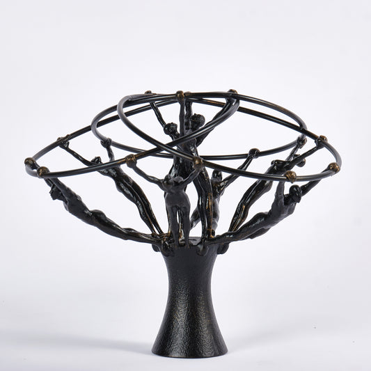 Black metal sculpture with abstract human figures on a white background