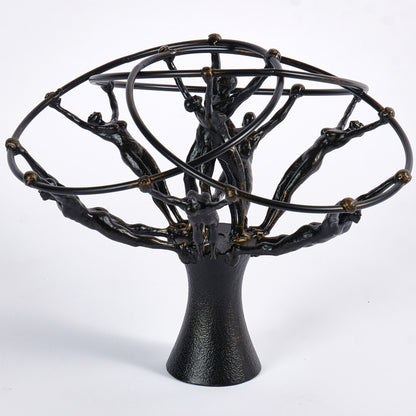 Black metal sculpture with circular top and tree-like base on a white background