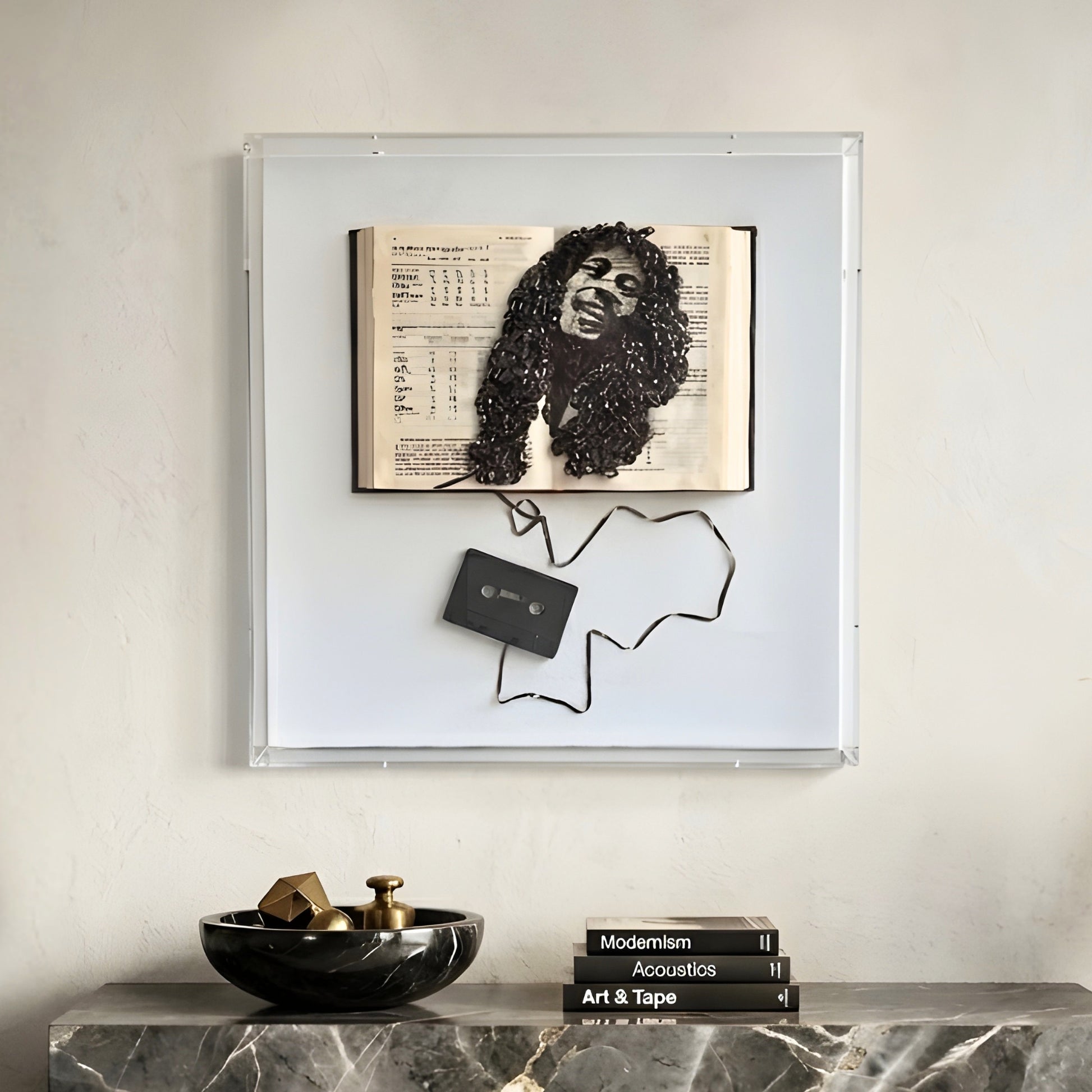 Framed artwork with a bob marley portrait and a cassette tape on a marble surface.