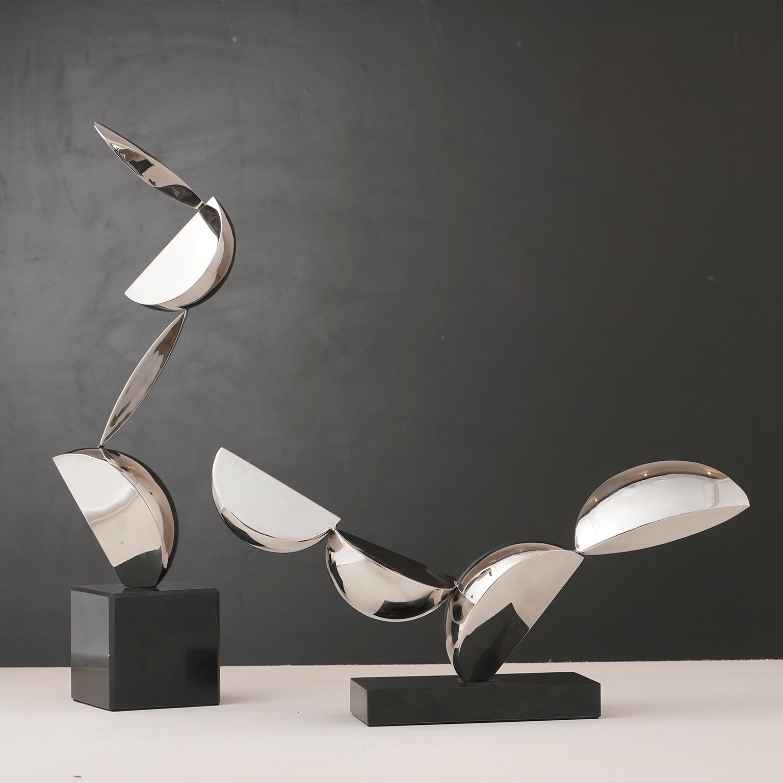 Abstract metallic sculpture on a black base against a gray background