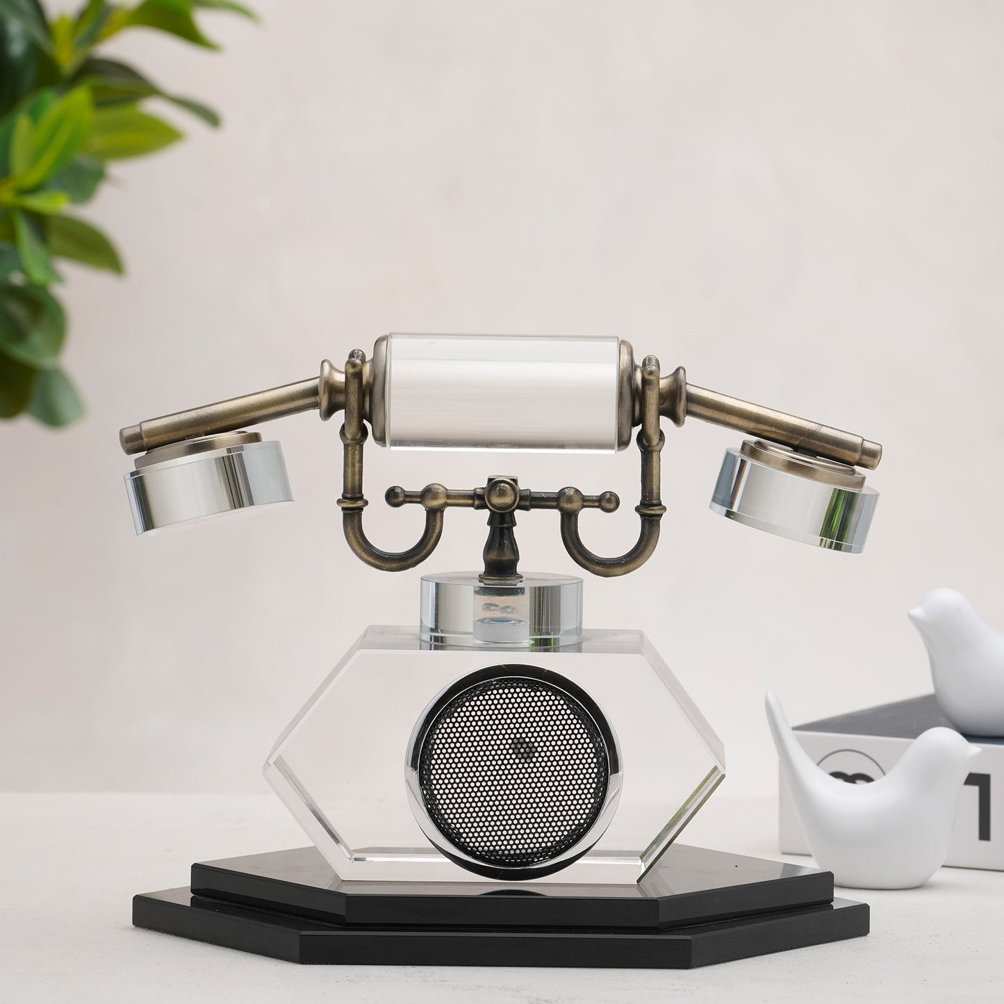 Vintage-style telephone decor on a white surface with a plant in the background