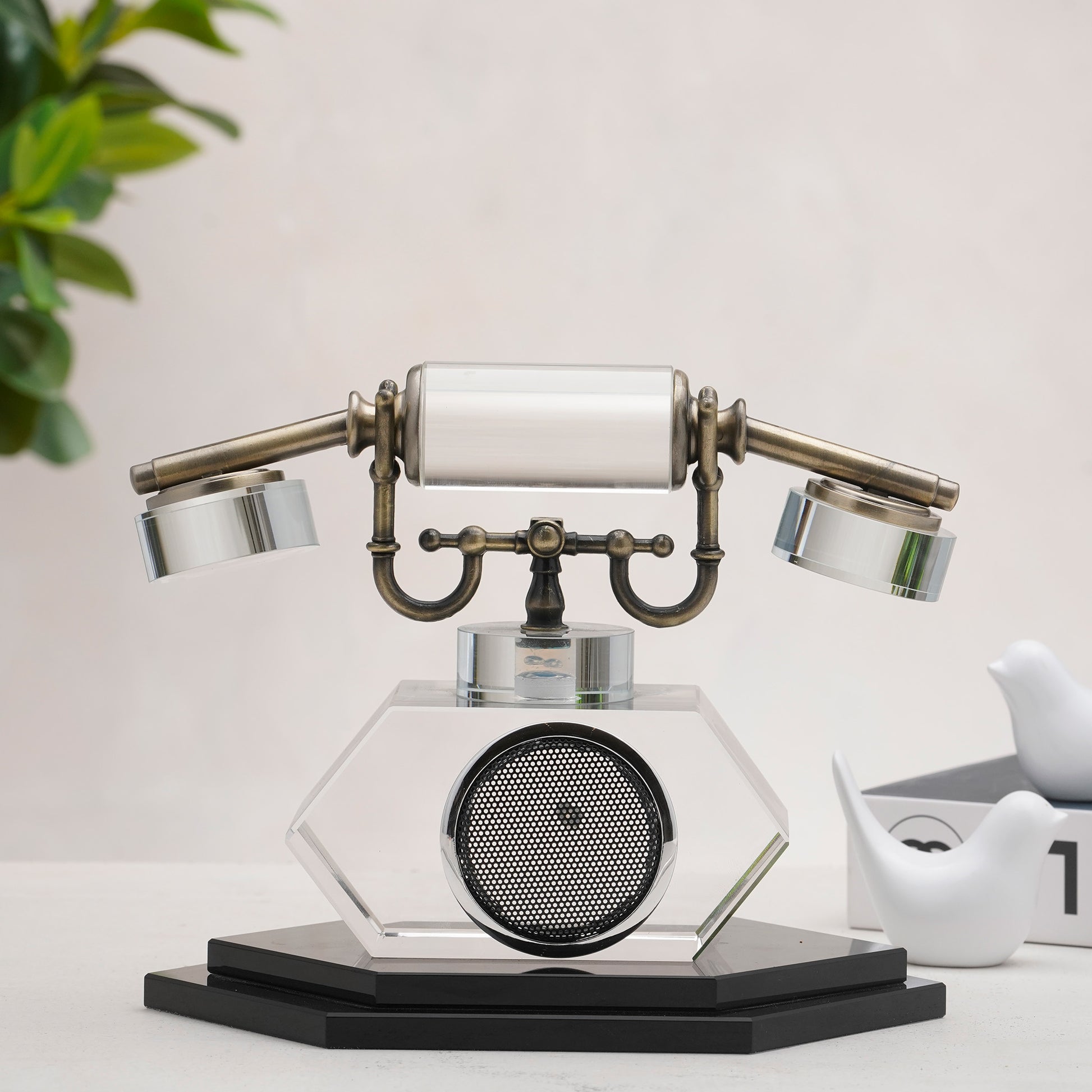 Vintage-style telephone decor on a white surface with a plant in the background