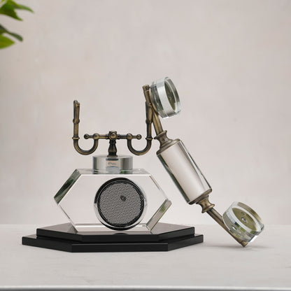 Decorative glass object resembling a vintage phone on a plain background