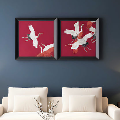 Two framed artworks of cranes on a red background above a white sofa.