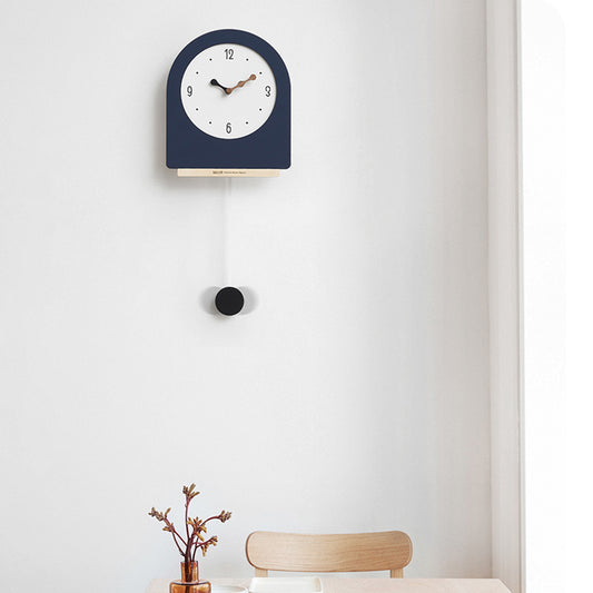 Navy blue wall clock with a pendulum on a white wall