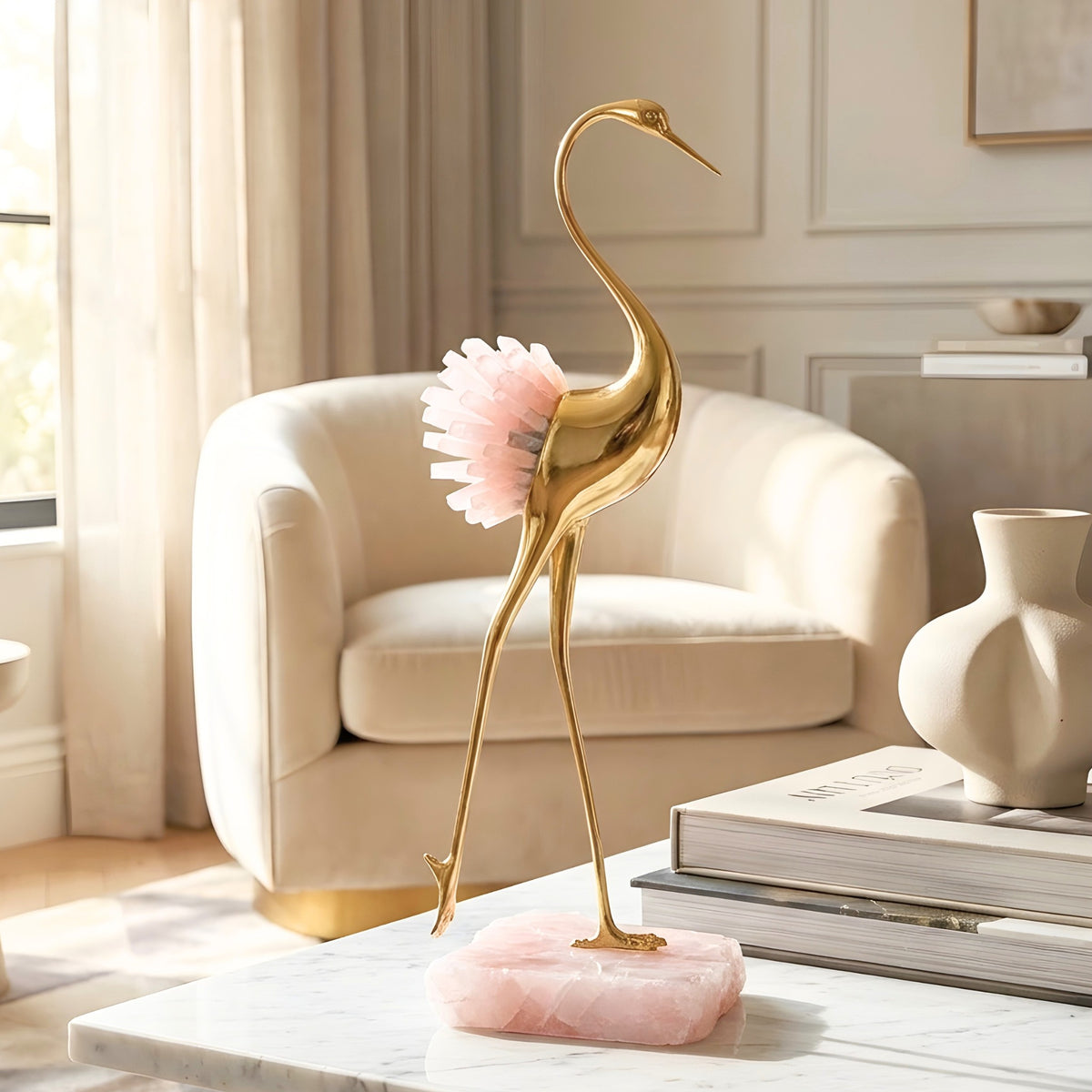 Ardea gold-toned metal bird with pink agate stone on a marble living room table