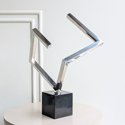 Axiom geometric stainless steel showpiece with polished silver finish and black marble base