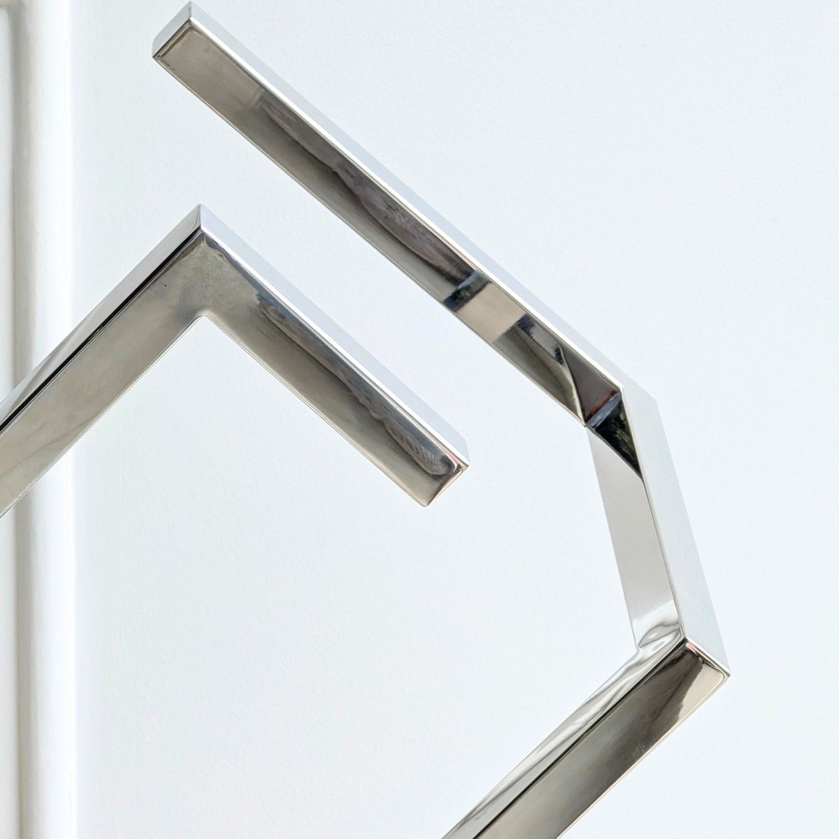 Close-up detail of Axiom polished stainless steel geometric sculpture