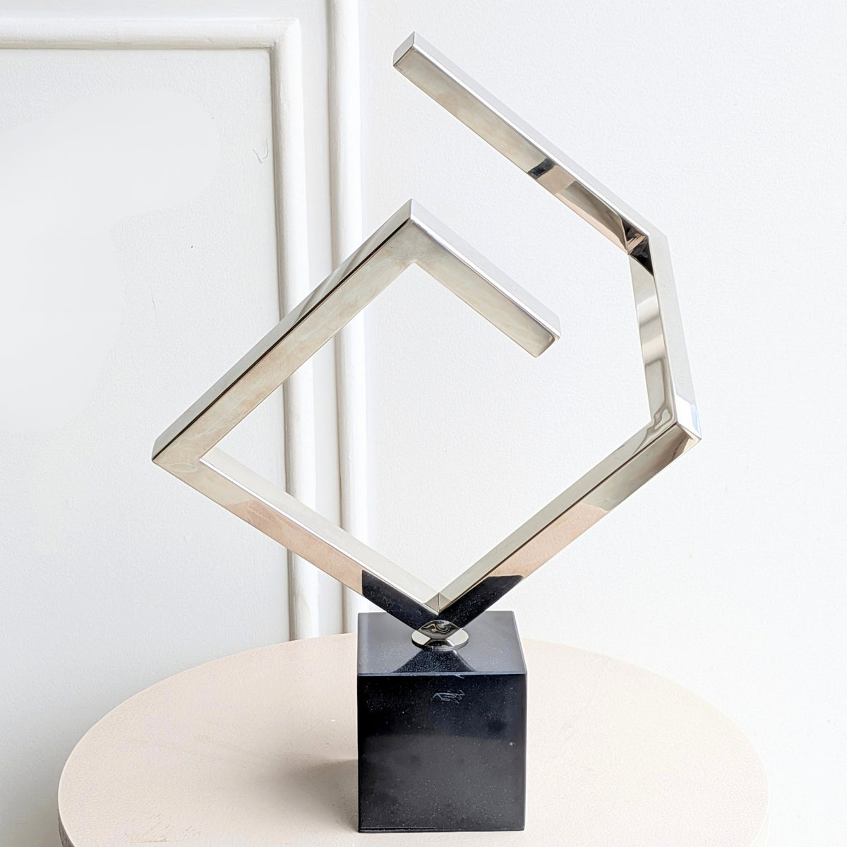 Front view of Axiom silver stainless steel geometric showpiece on black marble base