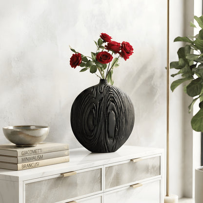 Round charcoal black sculptural ceramic vase styled with red roses on a white sideboard in a contemporary living room