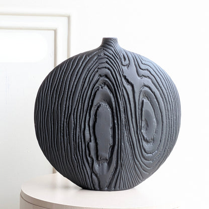 Front product view of large round black ceramic table vase with carved concentric woodgrain-inspired relief