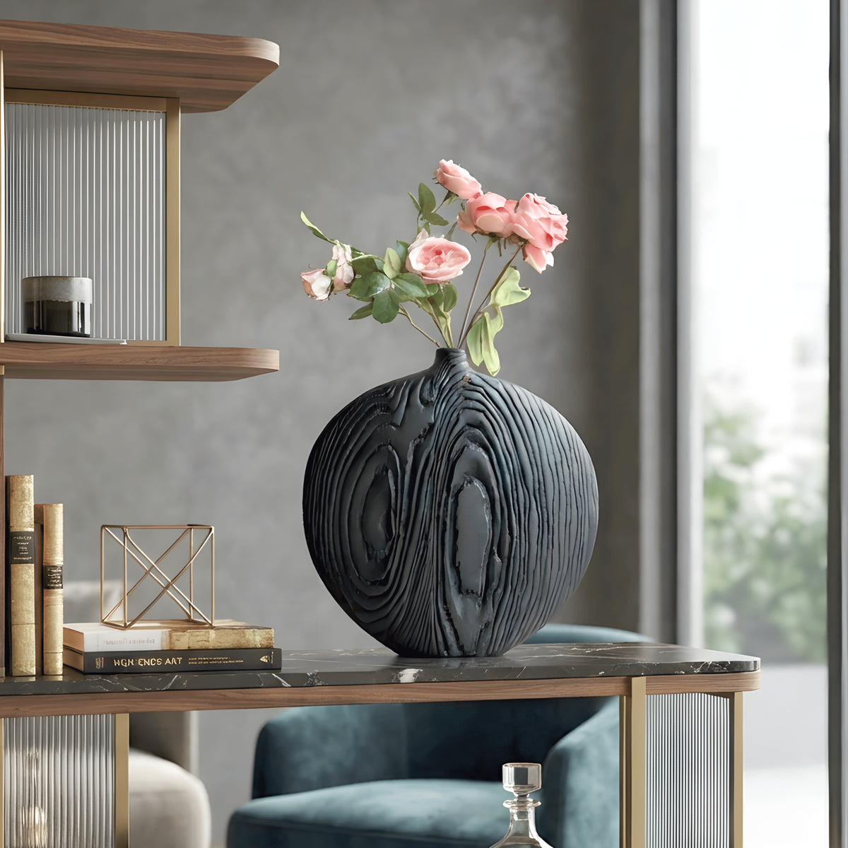 Statement black ceramic vase with pink floral stems styled on a study display shelf beside books