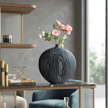 Statement black ceramic vase with pink floral stems styled on a study display shelf beside books