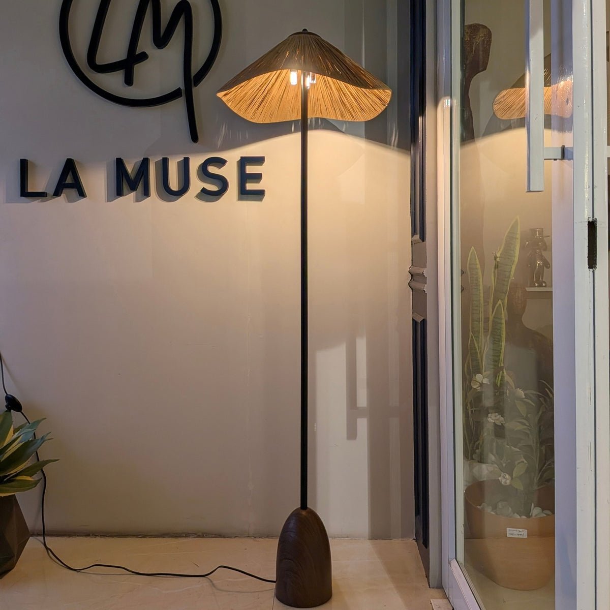 Canopy floor lamp illuminated at the La Muse showroom with a warm ambient glow