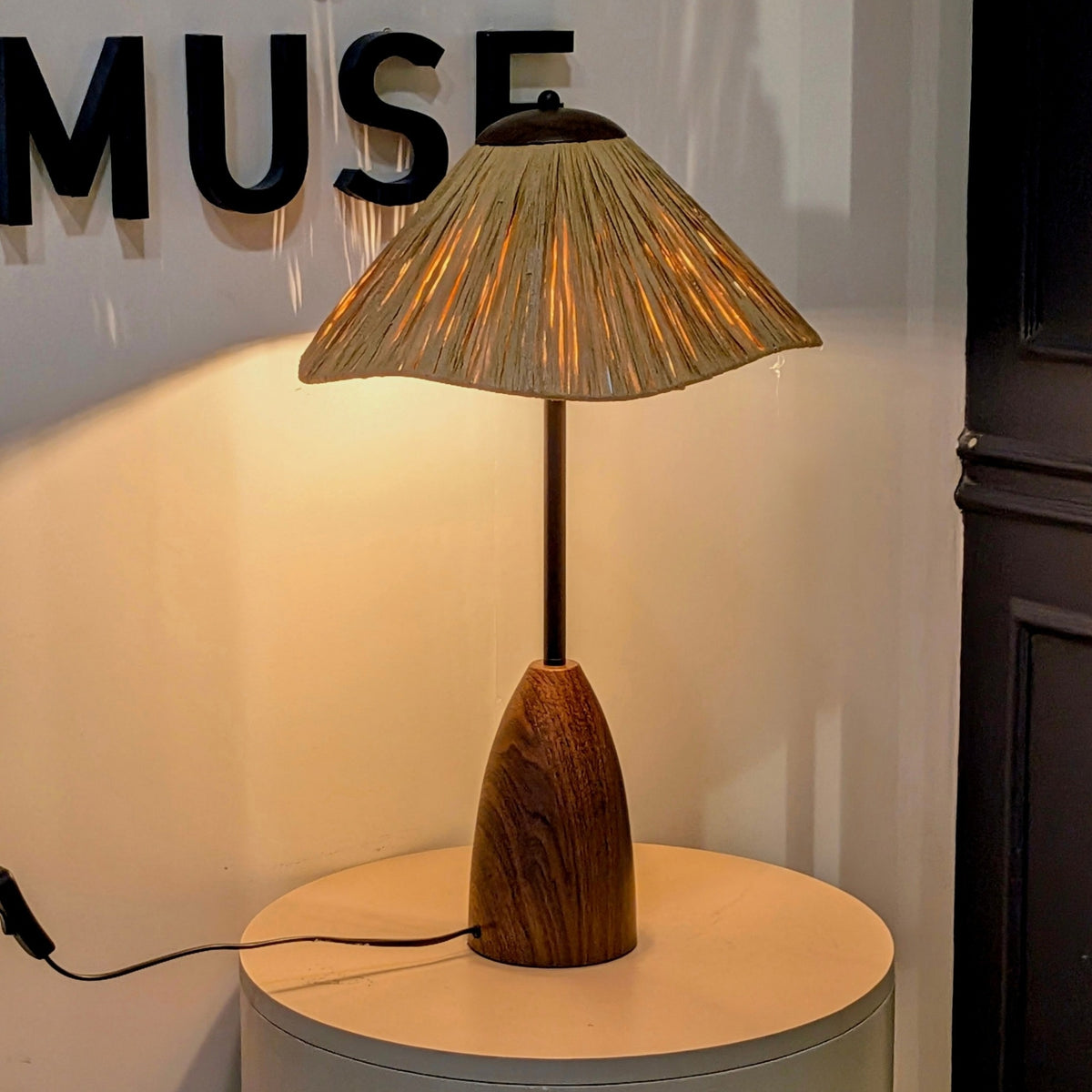 Canopy table lamp illuminated on a round table at the La Muse showroom