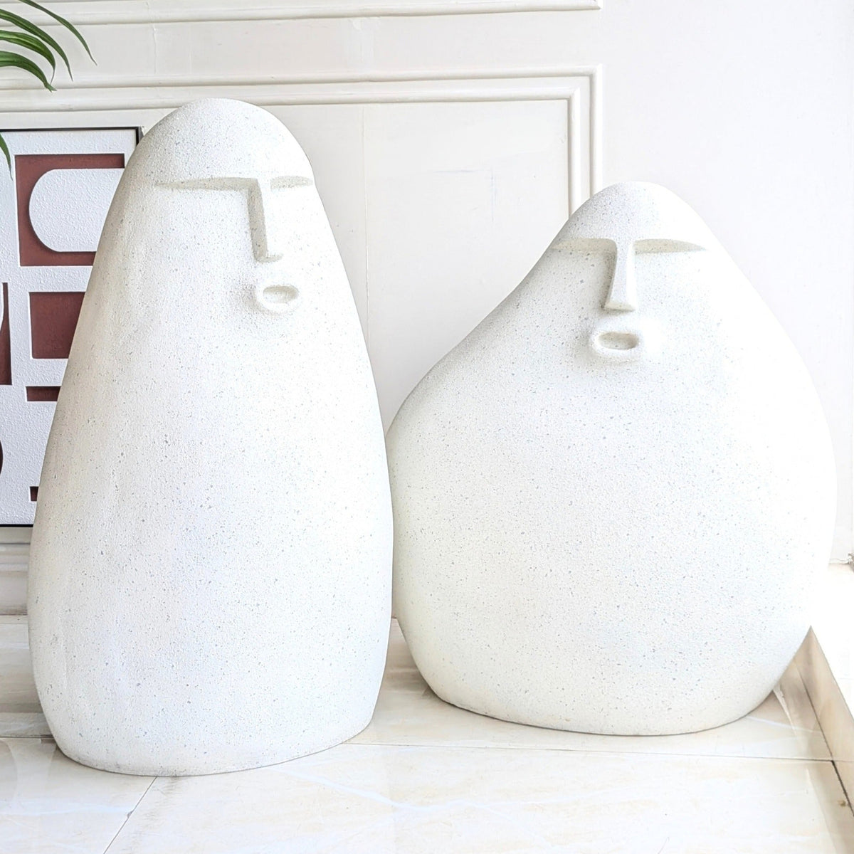 Carven resin human floor sculptures set of two with abstract faces and a carved stone finish