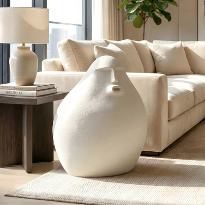 Carven small white human floor sculpture styled beside a cream sofa and side table