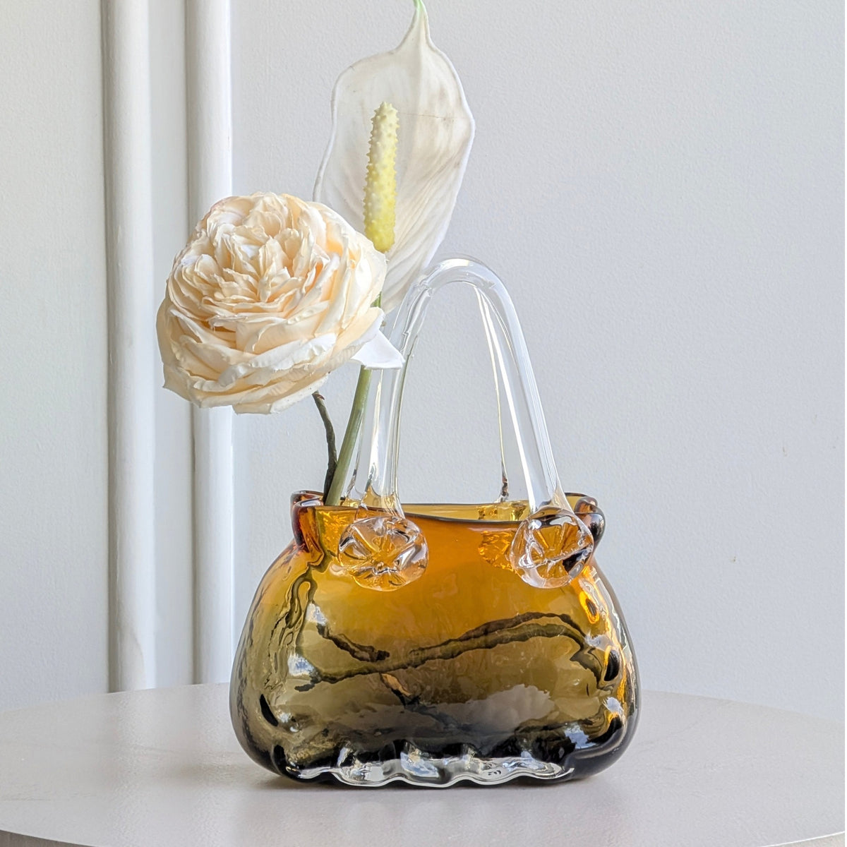 Couture amber crystal handbag vase with floral arrangement on a round table