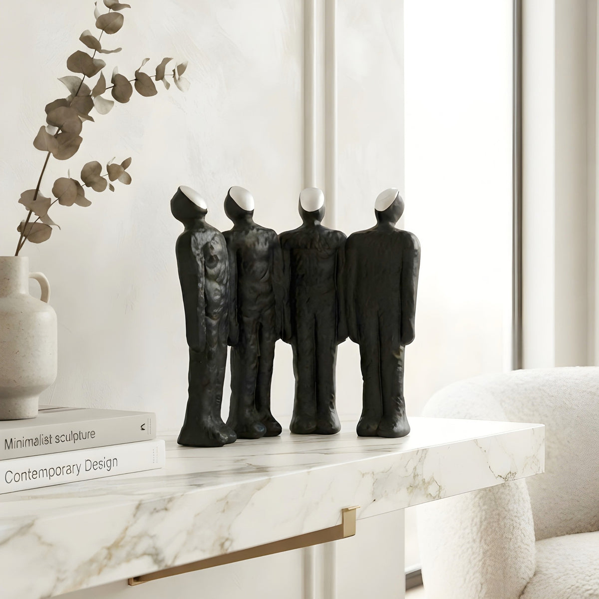 Ensemble textured charcoal four-person resin sculpture on a modern console table