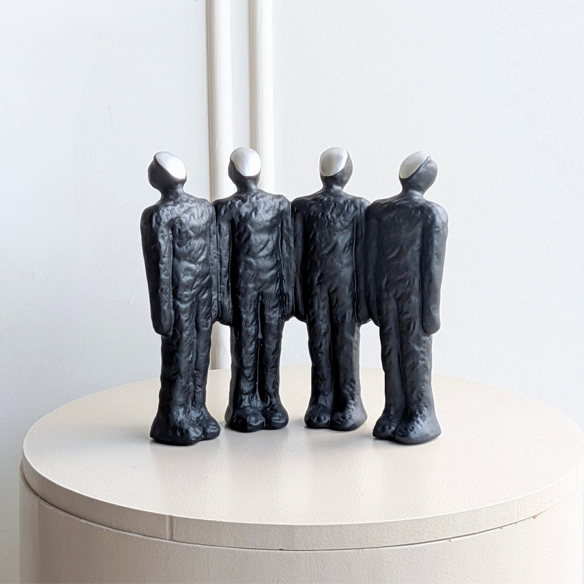 Ensemble abstract resin showpiece of four standing figures with contrasting light-toned faces