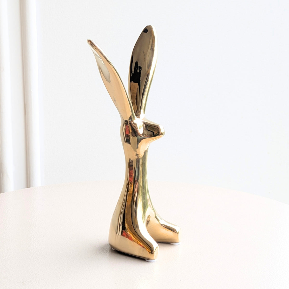 Close-up of Hareloom gold ceramic rabbit figurine showing its polished reflective finish and sculptural ears