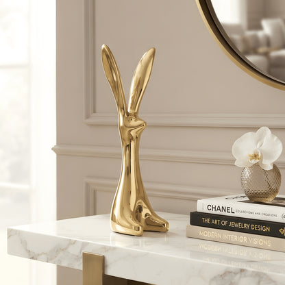 Two modern gold rabbit figurines styled on a marble foyer console beneath a round mirror
