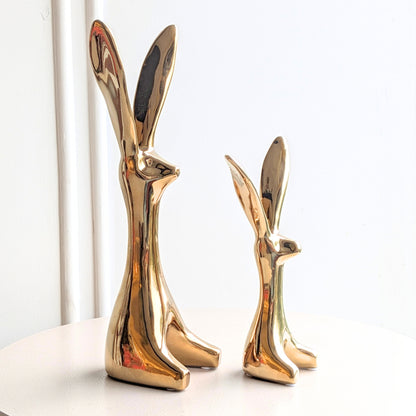 Hareloom polished gold ceramic hare sculptures in two sizes shown together on a display table