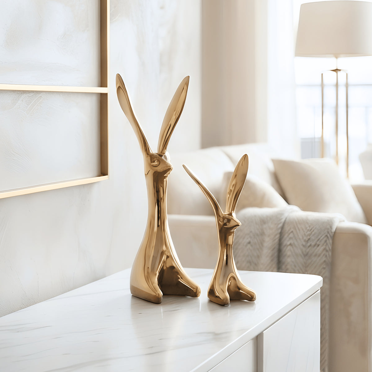 Gold ceramic rabbit figurine pair styled on a marble console in a modern luxury living room