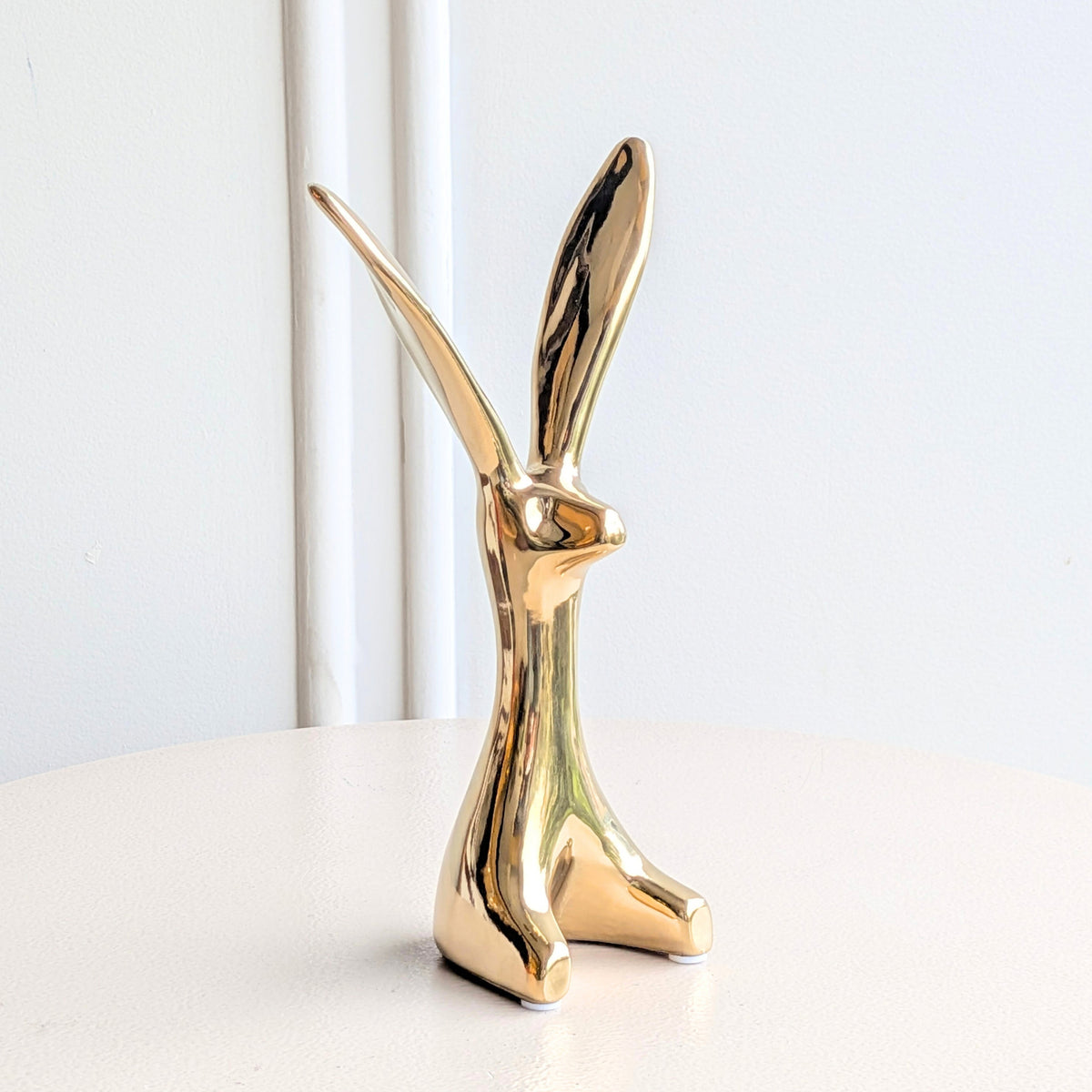 Small Hareloom gold ceramic rabbit figurine styled on a white marble shelf with books