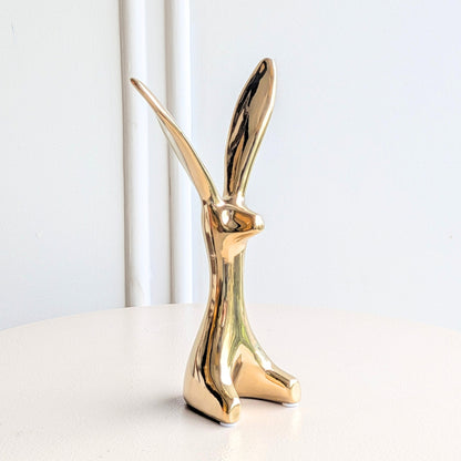 Small Hareloom gold ceramic rabbit figurine styled on a white marble shelf with books