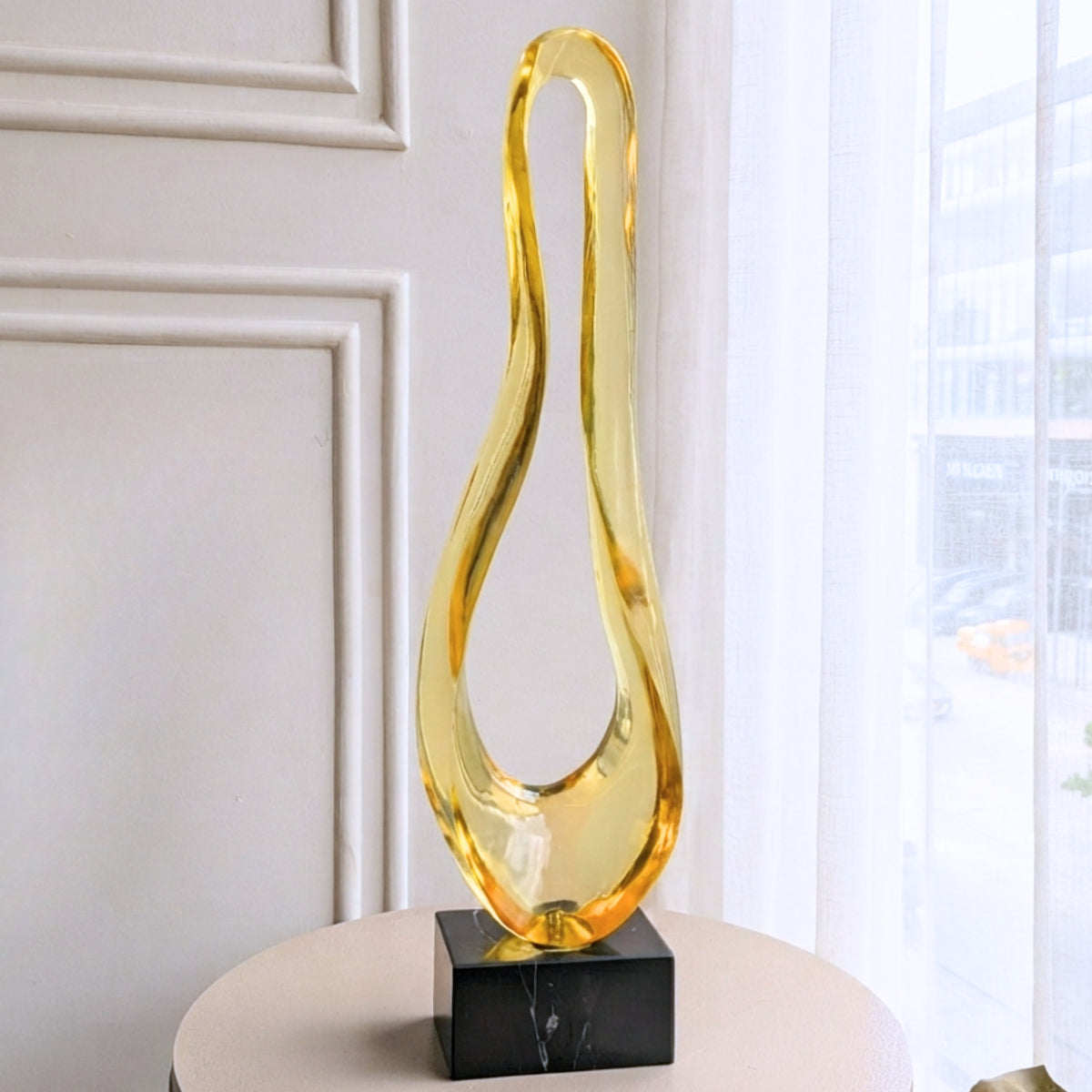 Loop gold resin and marble abstract showpiece displayed on a round pedestal