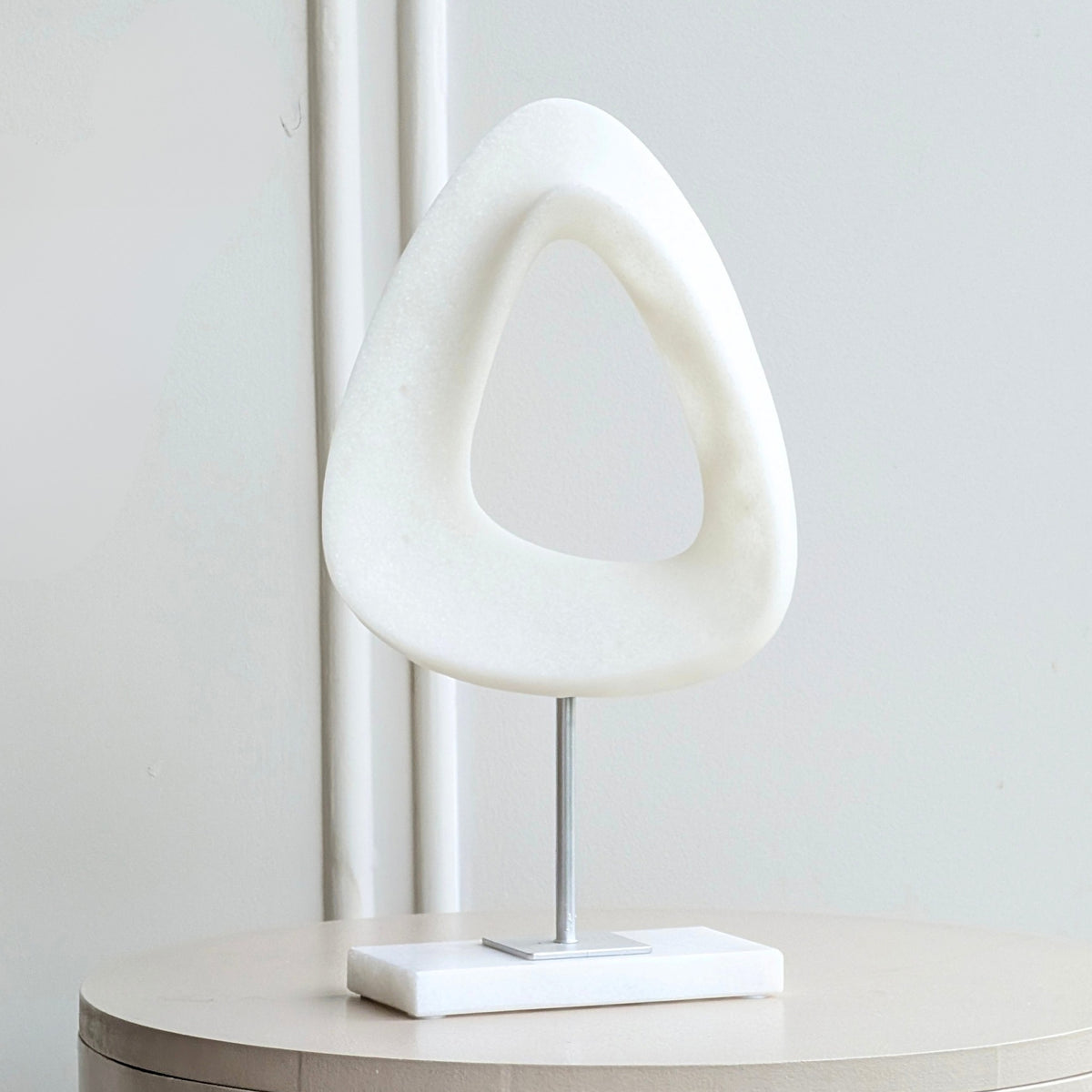 Front view of Loop sandstone resin sculpture with a white marble base