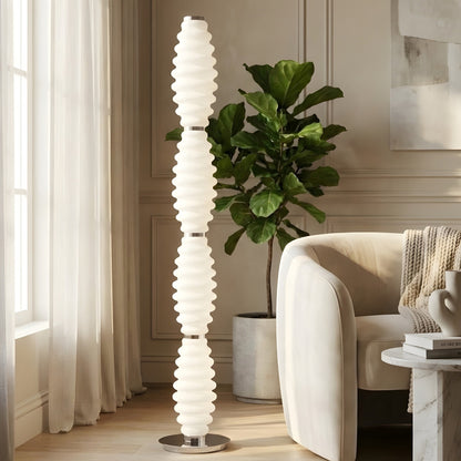 Luma Totem tall glass floor lamp beside lounge chair