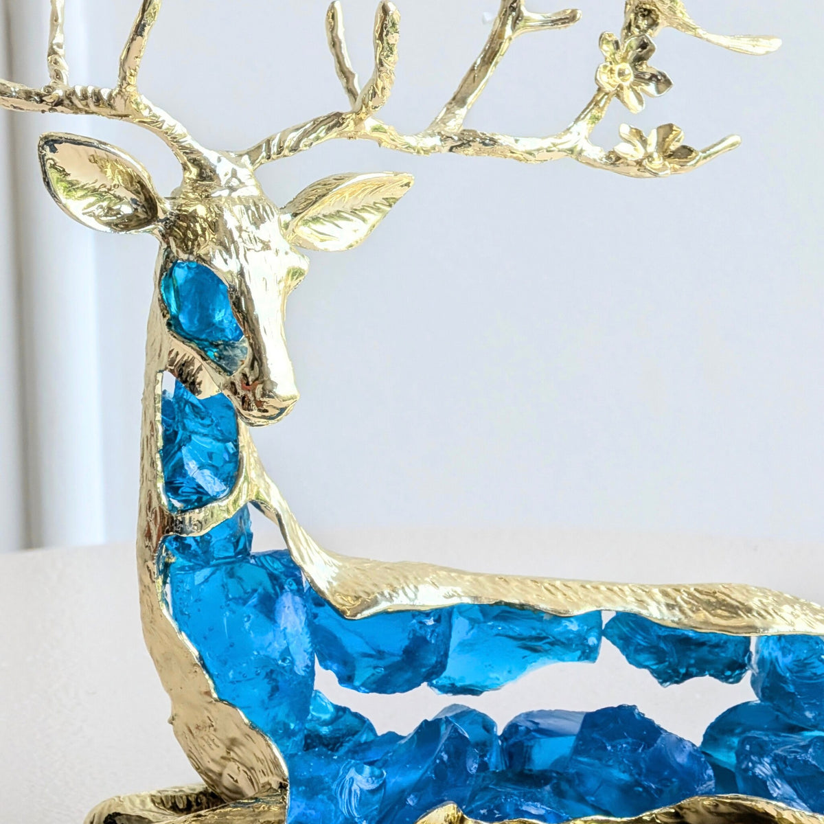 Close-up of Mystique sitting blue resin deer showpiece with gold-toned detailing