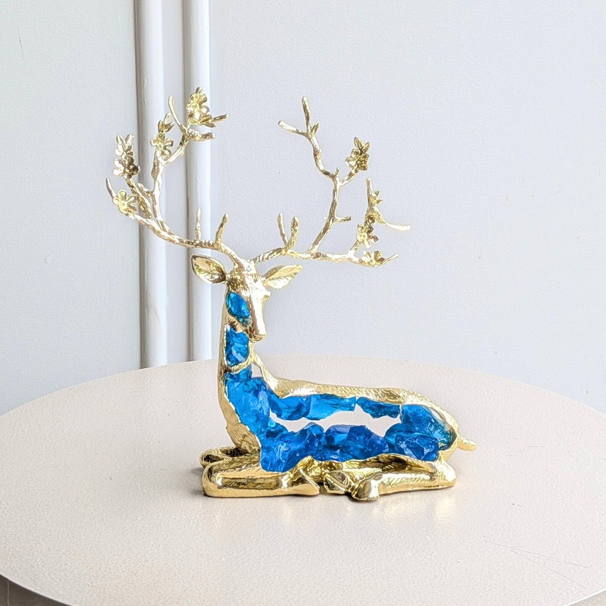 Mystique sitting deer showpiece with translucent blue resin body and gold-toned antlers