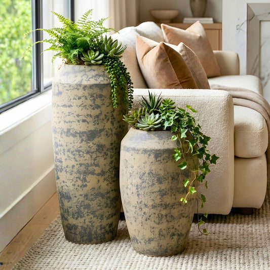 Patina ceramic floor pots styled with greenery beside a modern sofa