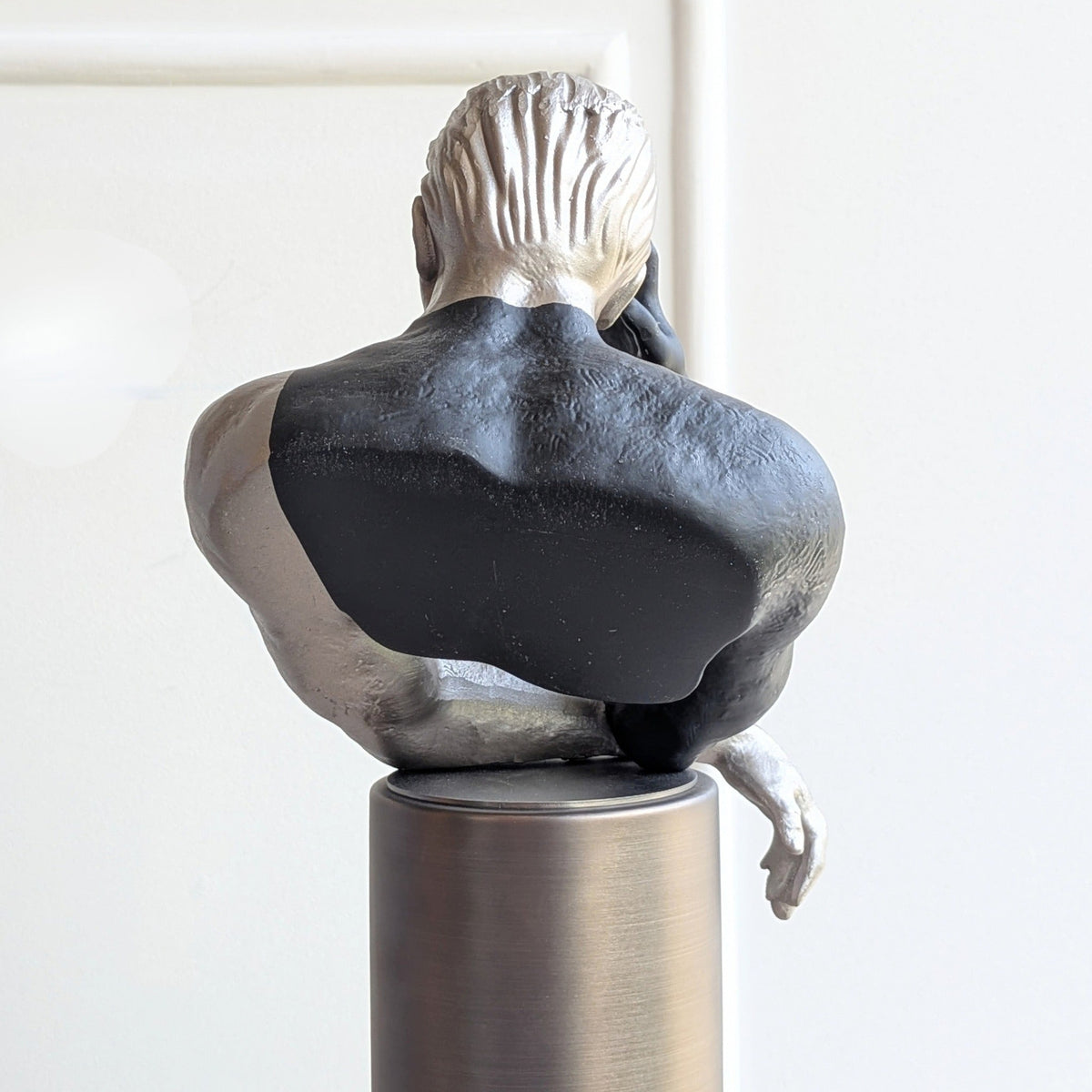 Rear detail of the Pensive sculptural human figurine and metal pedestal