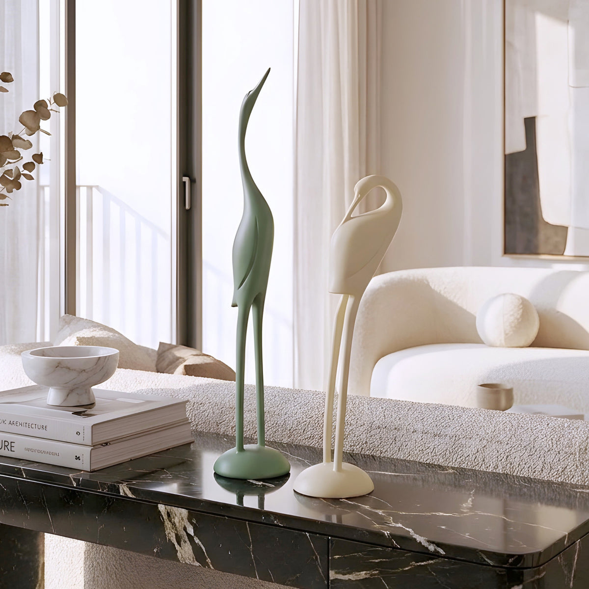 Green and ivory resin bird figurine duo styled on a marble coffee table in a modern living room