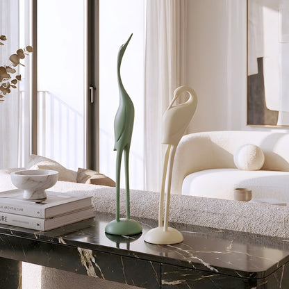 Green and ivory resin bird figurine duo styled on a marble coffee table in a modern living room