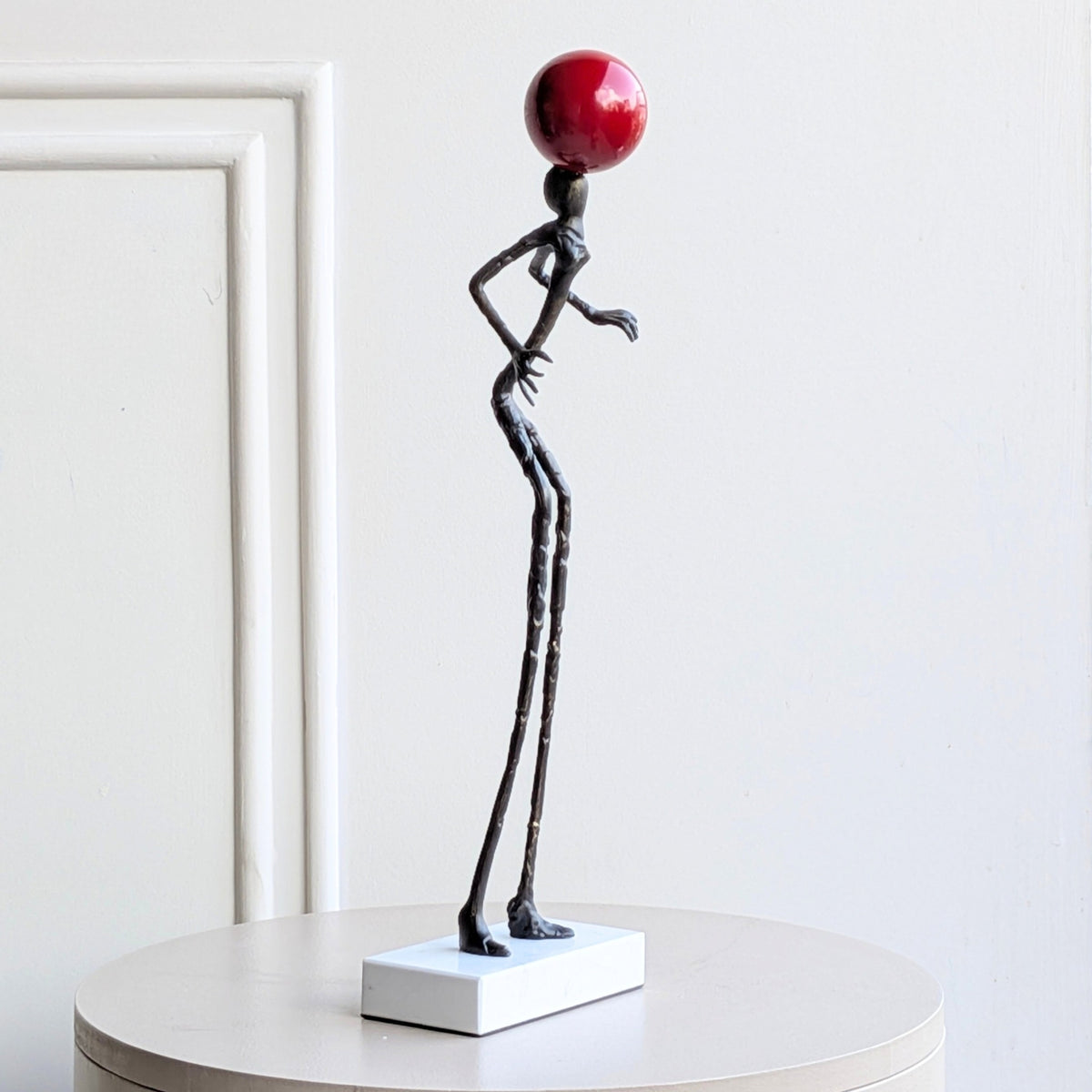 Side view of Redshift abstract metal figure with red orb on marble base